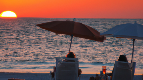 DALL·E 2023-11-08 21.04.24 - a sunset on the beach infront of a florida couple drinking with deckchairs.png