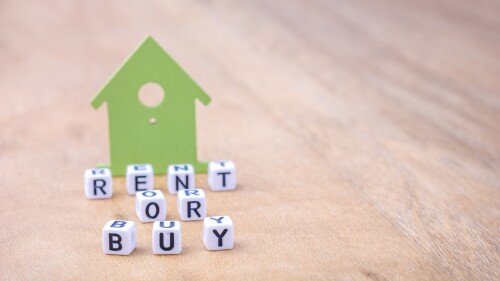 RENT OR BUY word of cube letters in front of green house symbols on wooden surface. Concept