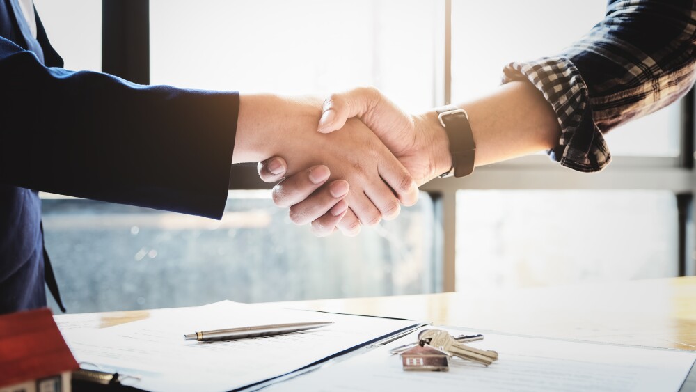 Focus on the congratulatory handshake. The real estate agent agrees to buy the home and hand the keys to the customer at the agent's office. conceptual agreement.