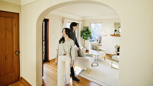 Wide shot of smiling couple walking into home for sale