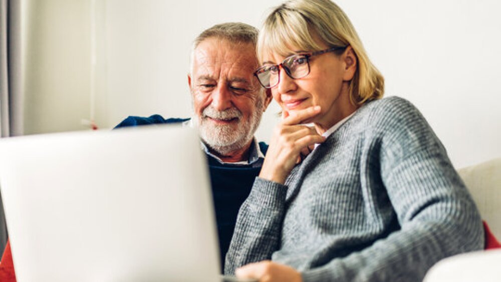 Couple looking at downsizing options on a laptop in their living room